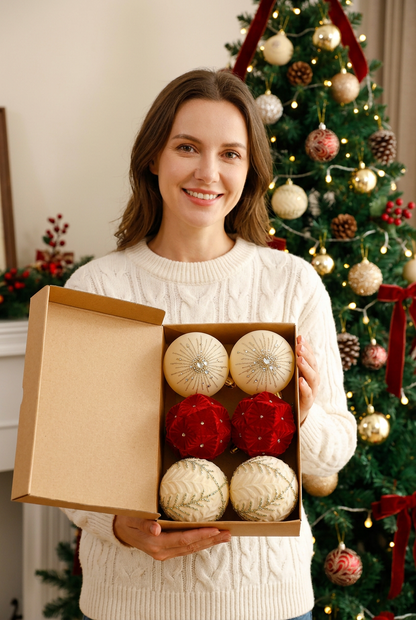 Female model holding boxed red ivory and gold Christmas ornament set